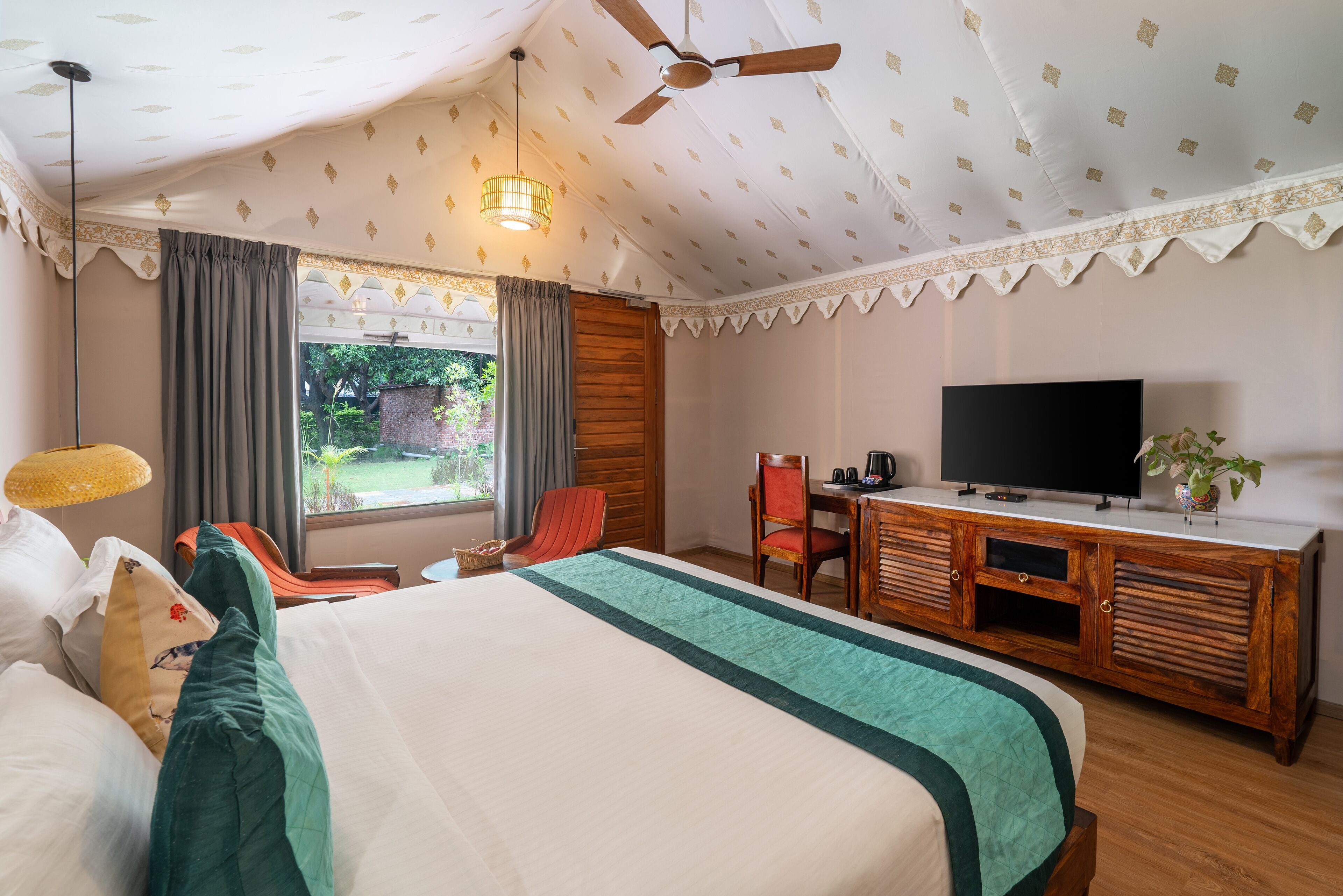 Une chambre d’hôtel avec un lit, un bureau avec une télévision, une chaise et une fenêtre avec des rideaux.