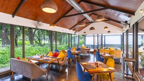 Ein modernes Restaurant mit Holzbalkendecken, großen Fenstern und farbenfroher Sitzgelegenheiten.