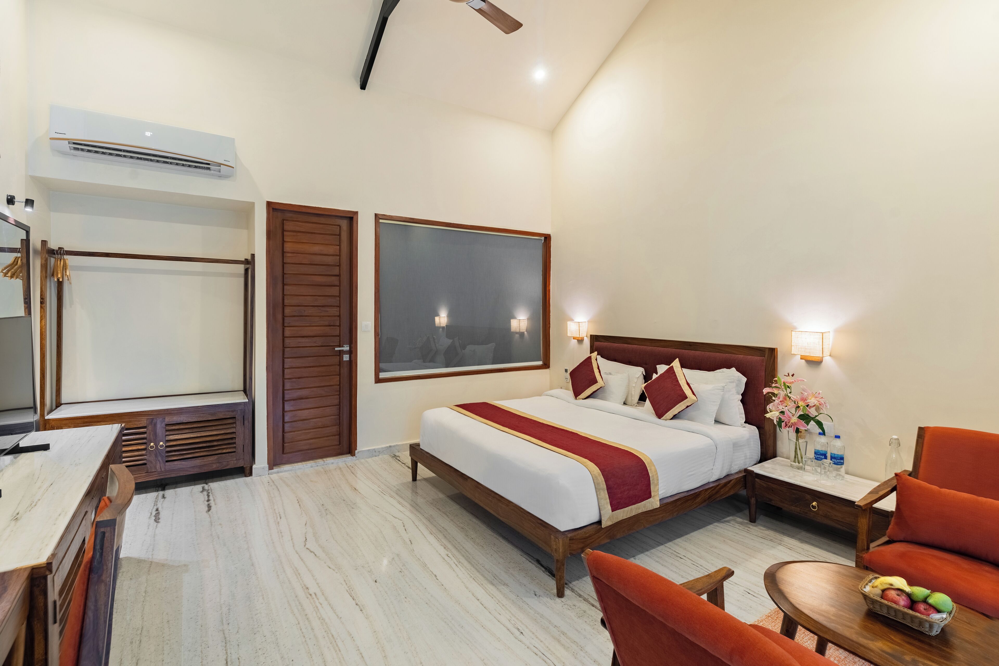 Een hotelkamer met een bed, een bureau, een stoel, een nachtkastje en een groot raam.