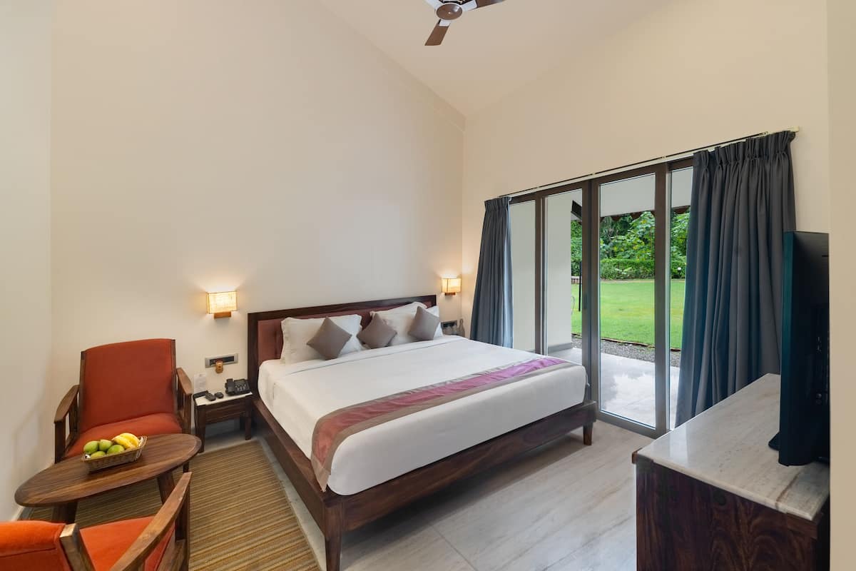 A hotel room with a large bed, a desk, a chair, a TV, and a view of the outdoors.
