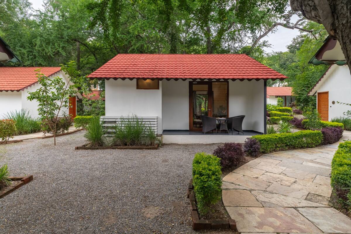 A small, single-story building with a red-tiled roof and a patio area with a table and chairs.