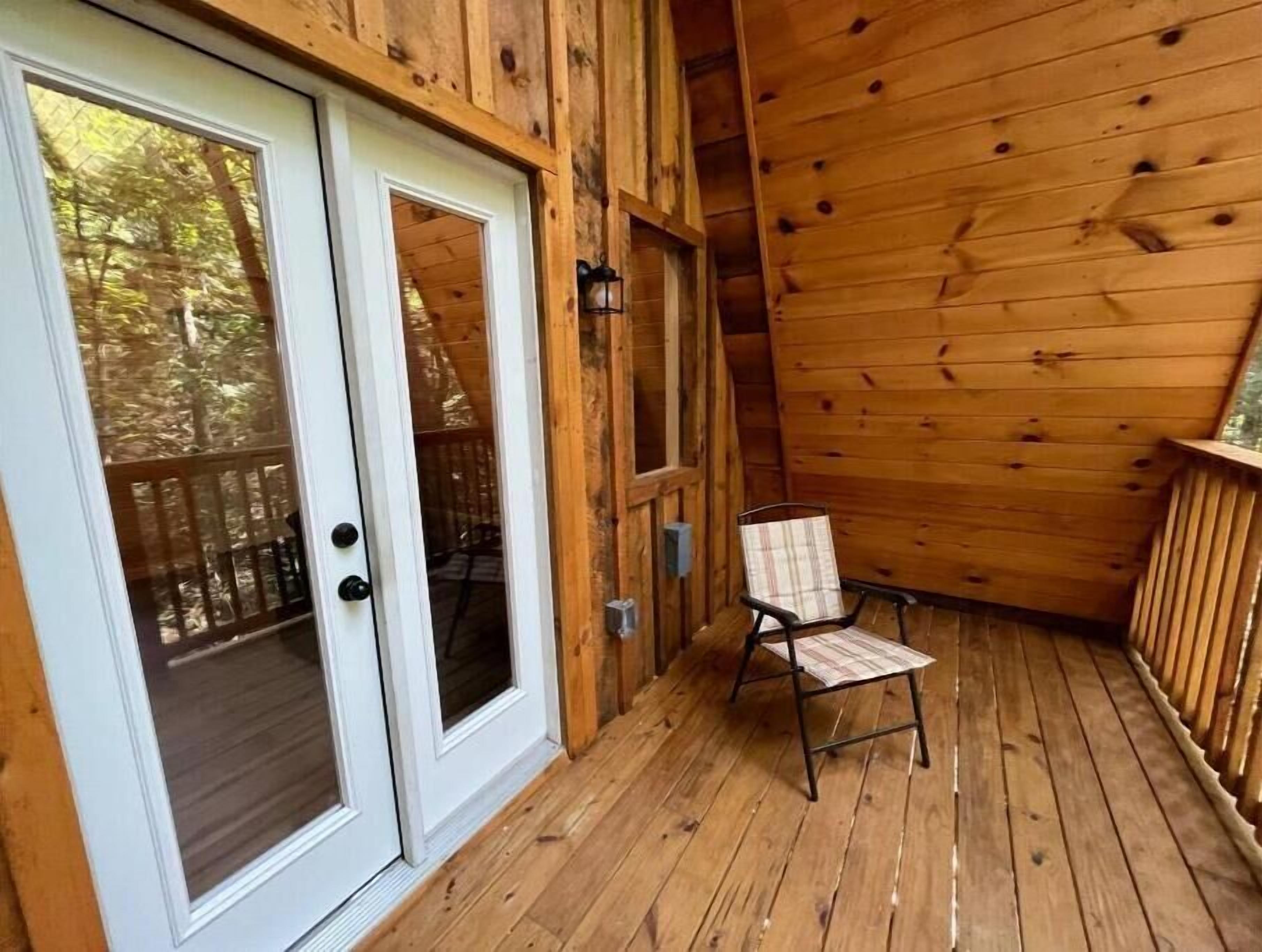 A wooden deck with a chair and a door with glass panels.