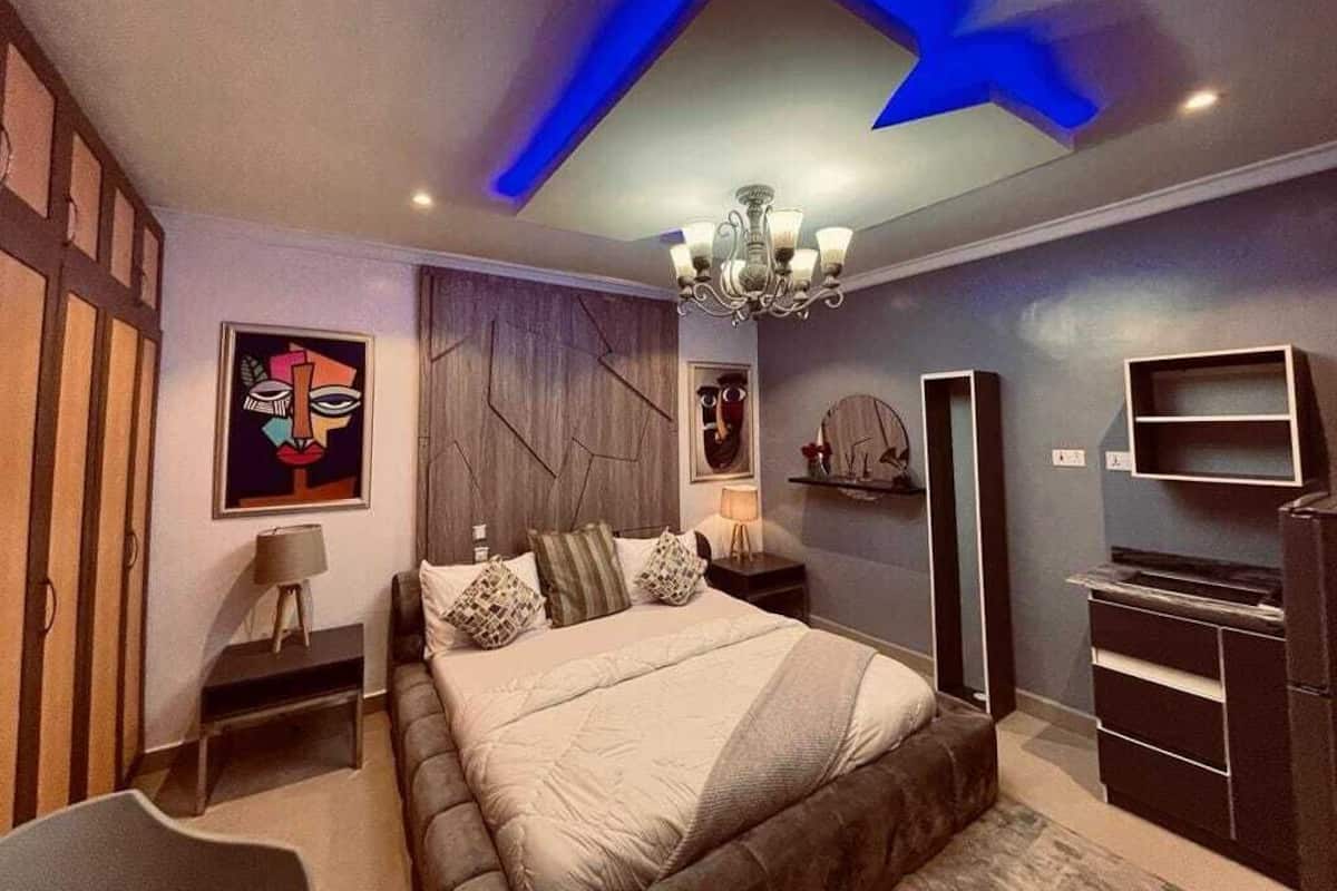 Ein modernes Schlafzimmer mit einem großen Bett, einer Chandelüster und einem Fernseher.