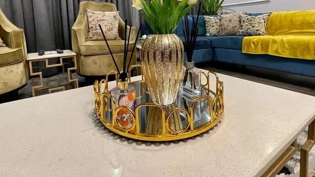 A modern living room with a round table, a sofa, and a chair. There is a vase with flowers on the table. - RBT Hotel (Lagos)