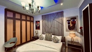 A bedroom with a large bed, a wardrobe, a desk, and a chair. - RBT Hotel (Lagos)