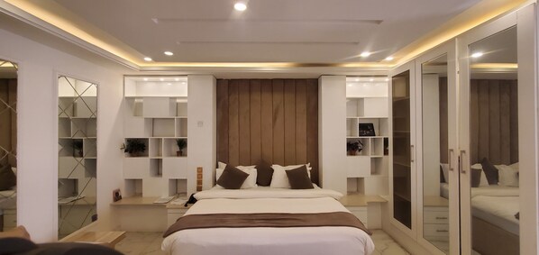 A modern bedroom with a large bed, built-in shelving, and a wardrobe with mirrored doors.