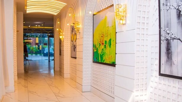 A corridor with a marble floor, white walls, and a large abstract painting. - The Palms Hotel (Abuja)