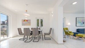 A modern dining area with a table and chairs, a window with a view, and a sofa in the background. - Villa Kristina Zadarvillas (Nin)
