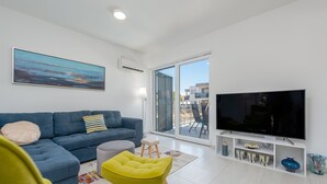 A modern living room with a blue sofa, a yellow armchair, a flat-screen TV, and a large window offering a view of the outside. - Villa Kristina Zadarvillas (Nin)