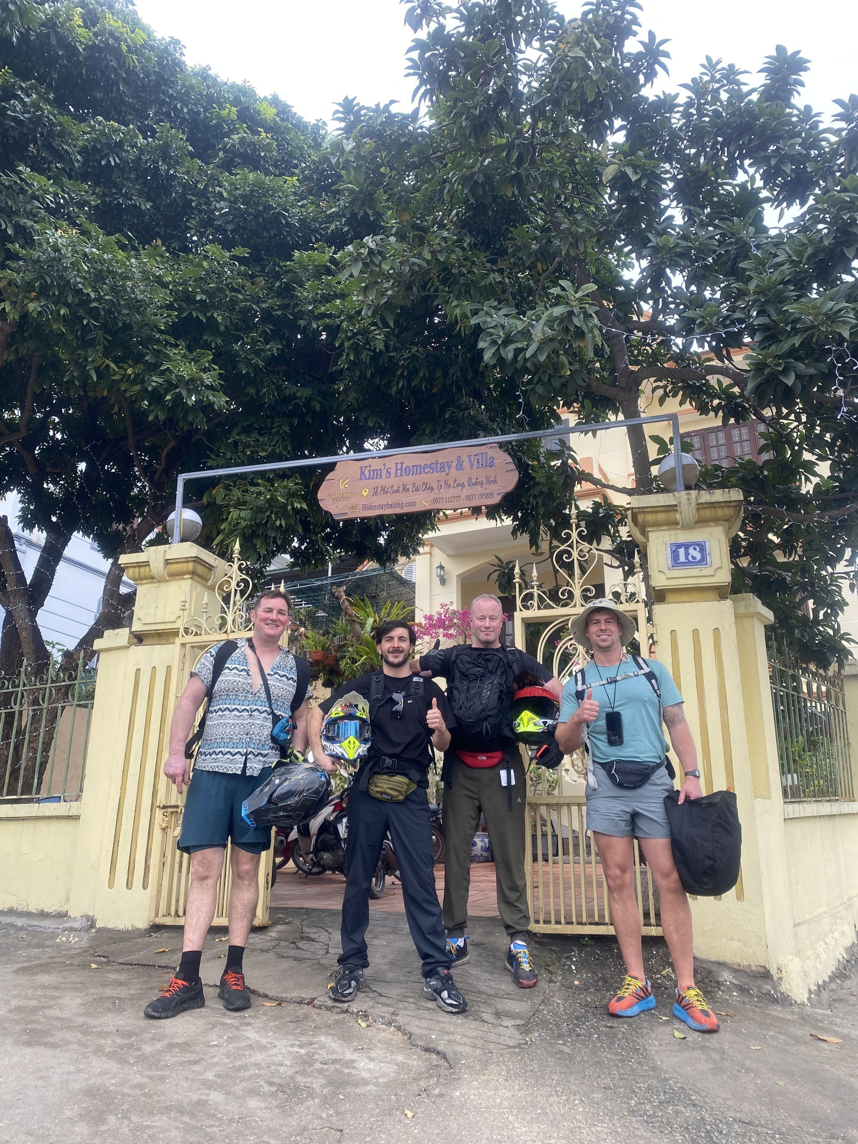 Un groupe de personnes se tient devant une porte sur laquelle est apposée une enseigne indiquant « Kim's Homestay & Villa ».