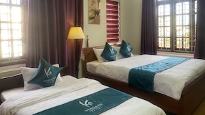 A hotel room with two beds, purple curtains, a lamp, and a painting. - Kim Homestay & Villa (Bai Chay)