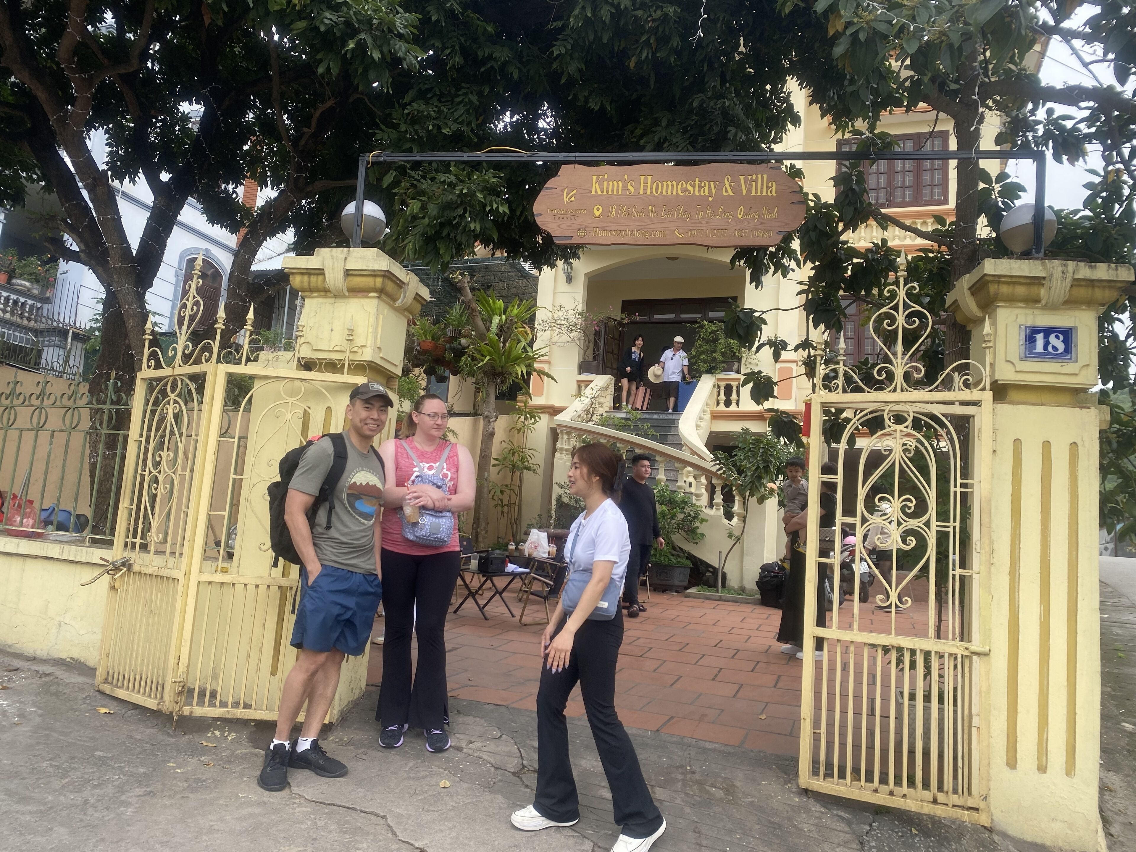 A gated entrance to Kim's Homestay & Villa with a signboard, a staircase, and a number '18' plaque.