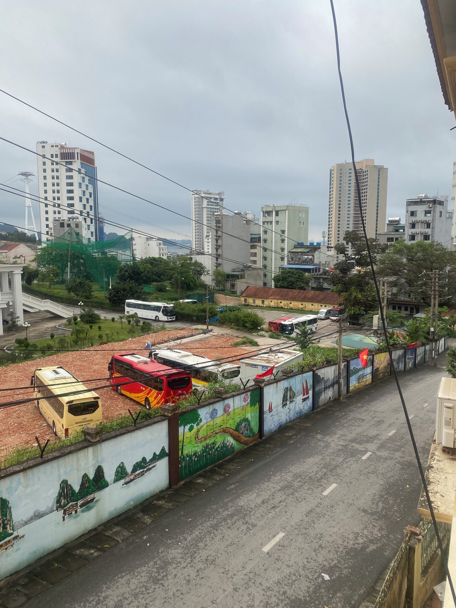A cityscape with multiple buses parked along a road, surrounded by buildings and greenery.
