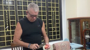 A man slicing a tomato on a table with various food items and kitchenware. - Kim Homestay & Villa (Bai Chay)