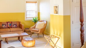 A cozy living room with a high ceiling, a wooden floor, a sofa, a chair, and a small table. - The Vesper  (Woodstock)