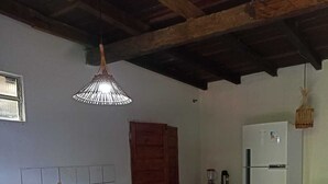 Una cocina con una isla de ladrillo, vigas de madera en el techo, un refrigerador blanco y un colgador de luces.