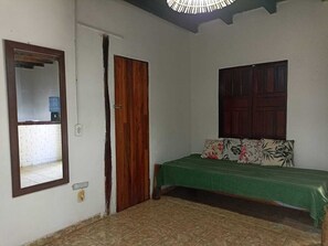 A room with a bed, a wooden door, a mirror, and a window.