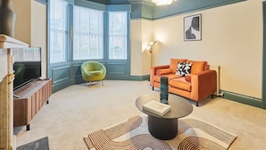 A living room with a sofa, armchair, coffee table, and a fireplace.