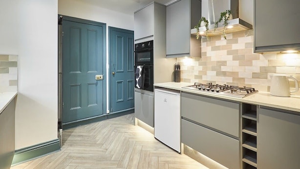 A modern kitchen with grey cabinets, a built-in oven, a dishwasher, and a gas stove.