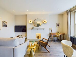 A modern living room with a sofa, chairs, a TV, a fireplace, and a dining area. - Bright & Stylish Home by Abbey Road Studios (Greater London)