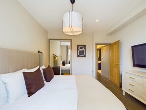 Ein Hotelzimmer mit einem großen Bett, einem Fernseher, einem Kleiderschrank und einem Spiegel.