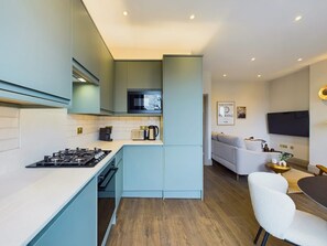 A modern kitchen with a built-in microwave, a gas stove, and a coffee maker. - Bright & Stylish Home by Abbey Road Studios (Greater London)
