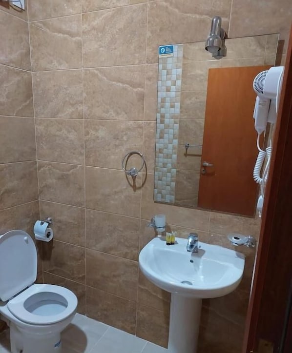 A bathroom with a toilet, sink, and shower area. - Askant Al Azizyia Hotel (Makkah)