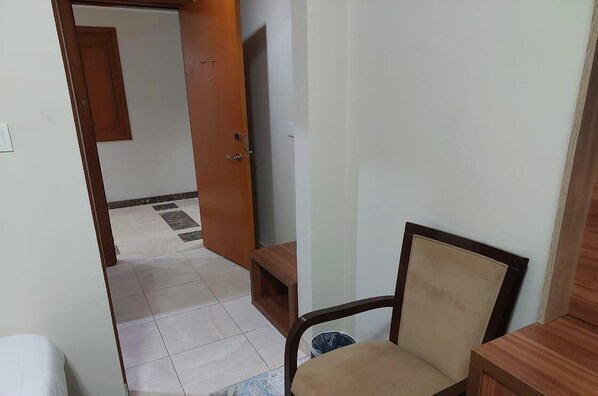 Une pièce avec une porte en bois, un téléviseur, une chaise et une poubelle.
