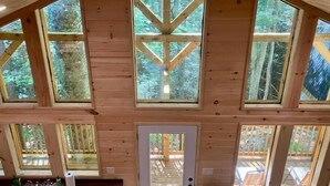 Una cabaña con amplias ventanas, una cocina con fregadero y una puerta que da al exterior.