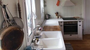 A compact kitchen with white cabinetry, a built-in oven, and a hanging pot rack.