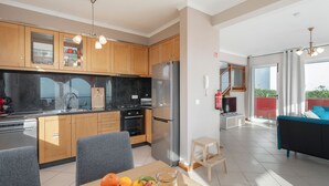 Une cuisine moderne avec des meubles en bois, un réfrigérateur en acier inoxydable et un coin repas avec une table mise pour deux personnes.