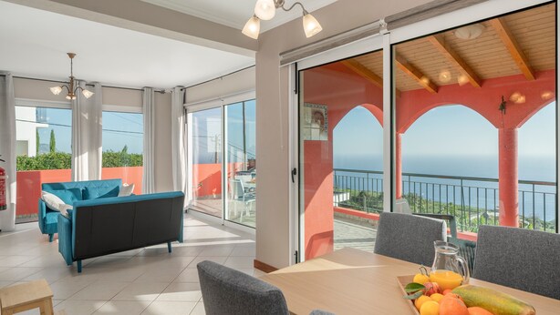 Un balcon spacieux avec une table préparée pour le petit-déjeuner, un canapé et une vue sur la mer.