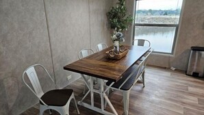 Zona pranzo con tavolo in legno, sedie bianche e una panca.
