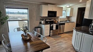 Una cucina moderna con mobili bianchi, elettrodomestici in acciaio inossidabile e un'area pranzo con tavolo e sedie in legno.