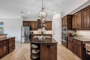 A kitchen with wooden cabinets, stainless steel appliances, and a central island. - Diagonal Dreams Lake House | Concierge Services (Horseshoe Bay)