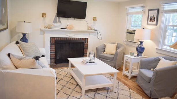 A living room with a fireplace, a television mounted above it, and two sofas. - Adorable two bedroom sleeping 6 in West Dennis, .6 miles to the beach! (West Dennis)