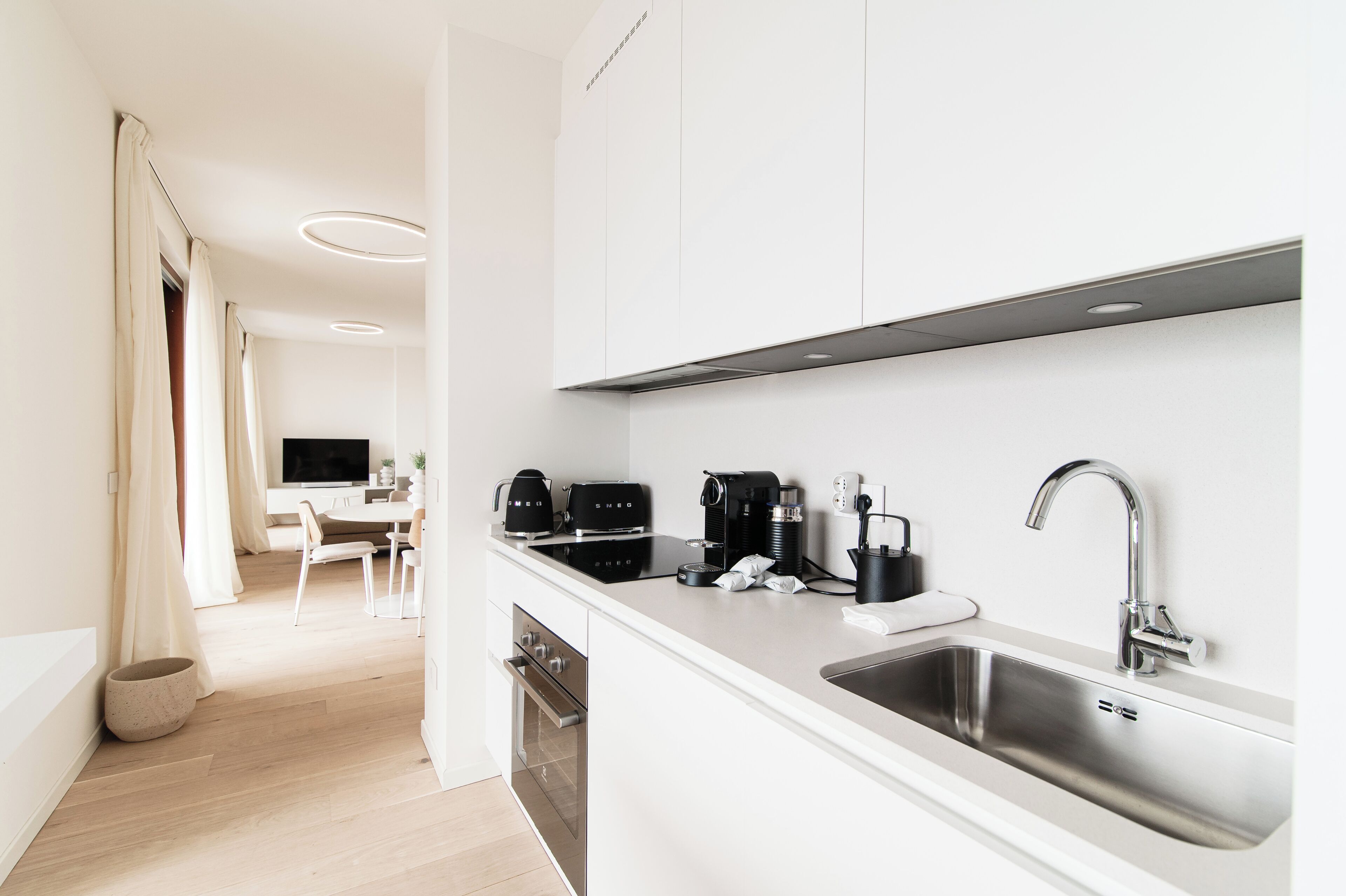 A modern kitchen with a stainless steel sink, a coffee maker, and a kettle.