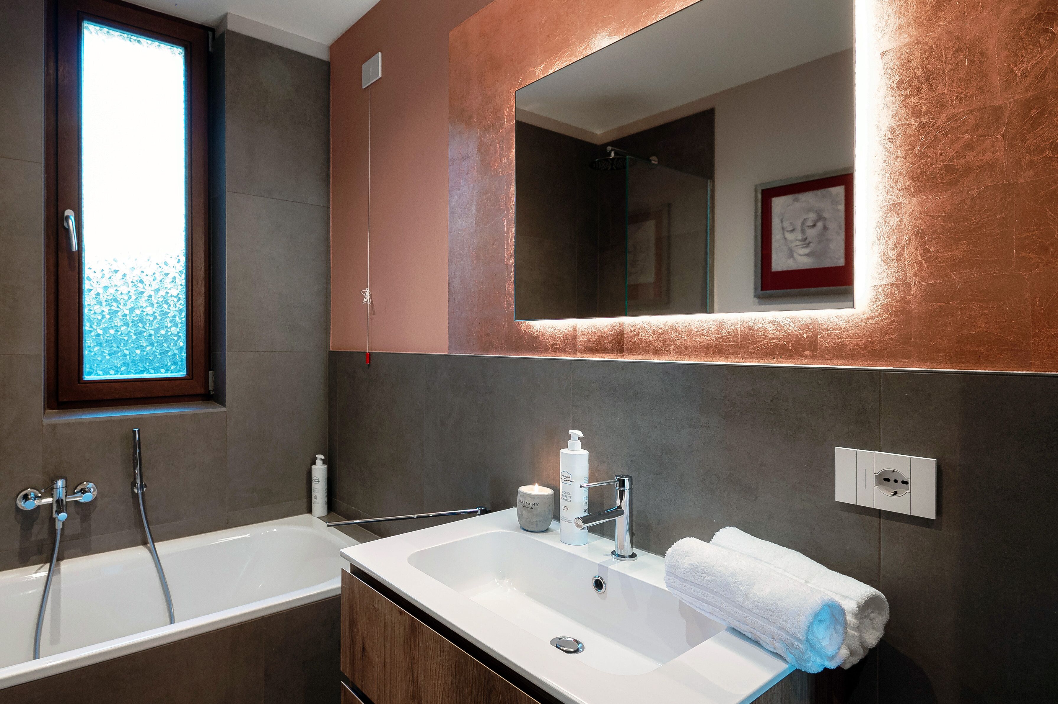 A modern bathroom with a large mirror, a bathtub, and a sink.