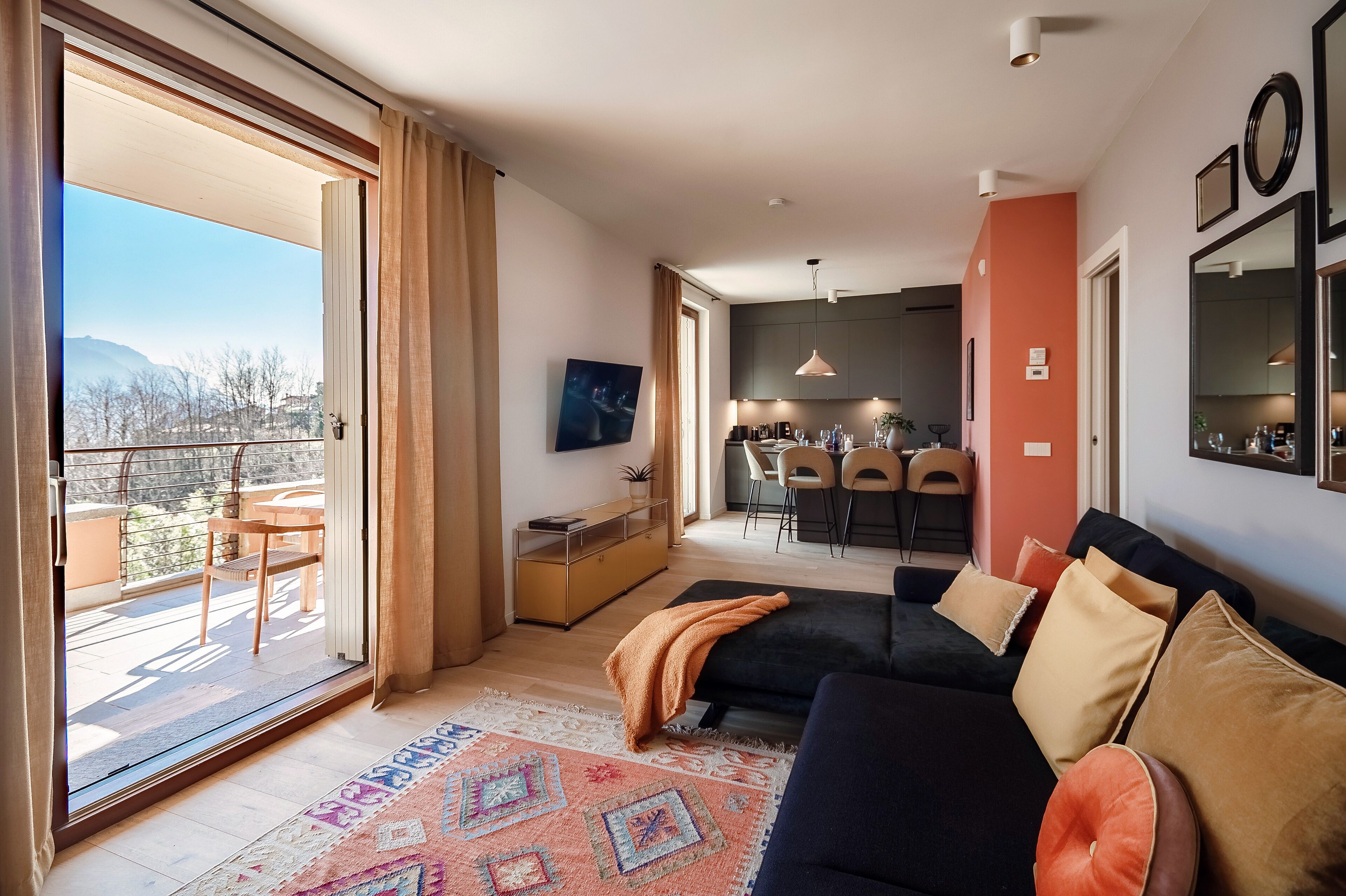 Un salón moderno con un sofá, un tapete estampado y vistas a un balcón exterior.