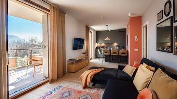 Un salón moderno con un sofá, un tapete estampado y vistas a un balcón exterior.