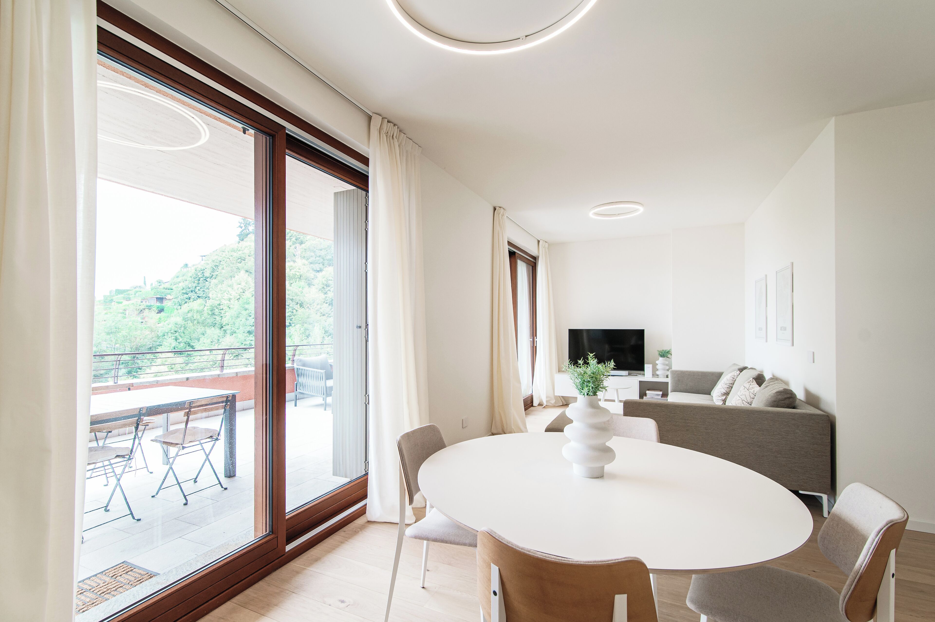 Una sala de estar moderna con una mesa redonda de comedor, sillas, un sofá y un televisor.