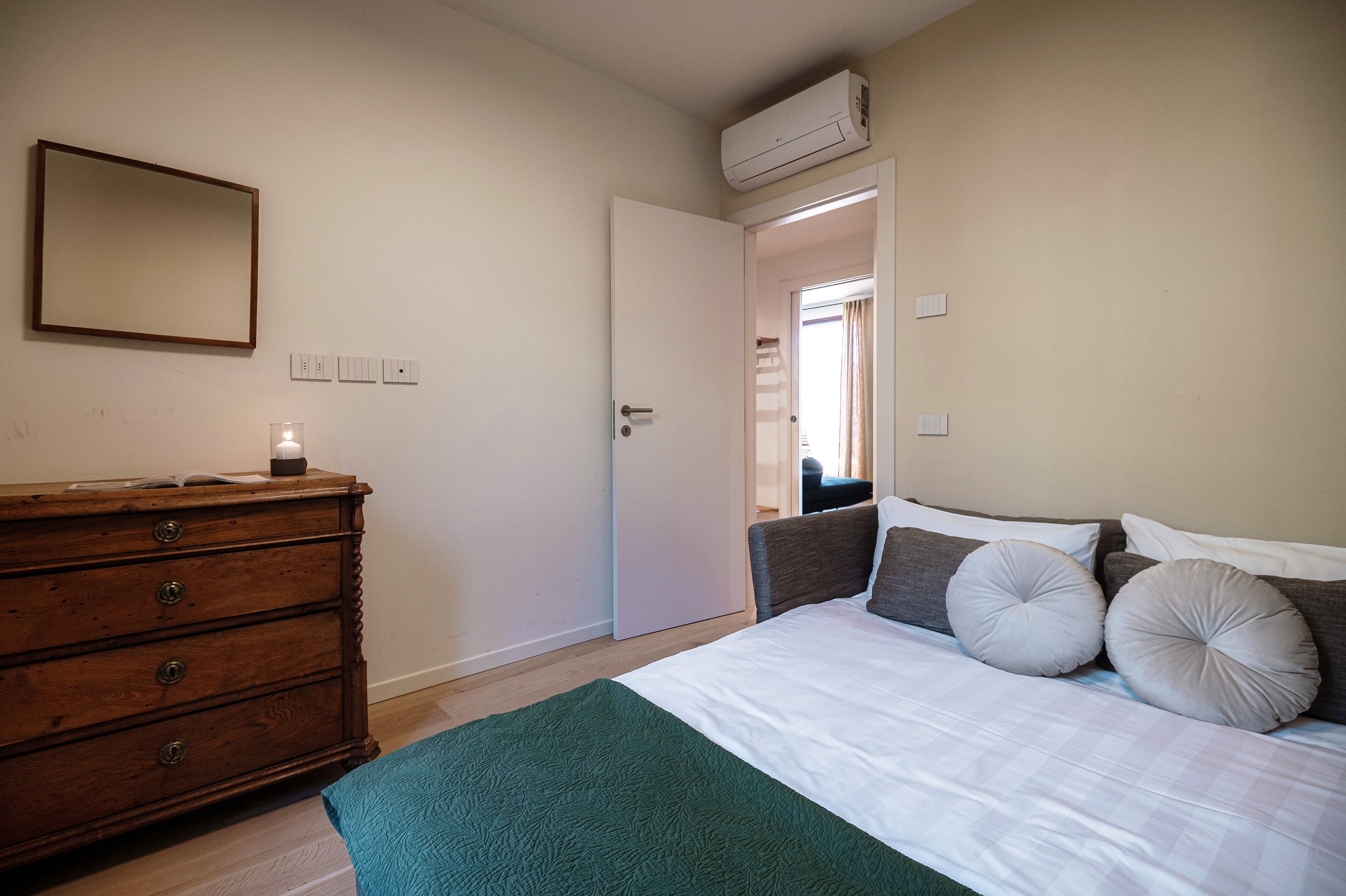 Une chambre à coucher comprenant un lit, une commode et un appareil de climatisation.