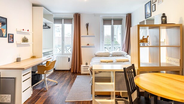Une chambre d’hôtel moderne équipée d’un lit, d’un bureau, d’une chaise, d’une table à manger et d’une bibliothèque.