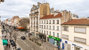 Une vue de rue avec un immeuble doté d’une grande façade en pierre, une succursale de la banque BNA et un magasin BRED.