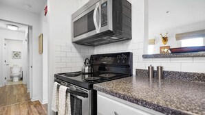 A modern kitchen with a stainless steel stove, microwave, and granite countertop.