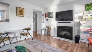 A modern living room with a fireplace, a flat-screen TV, and a dining area with a table and chairs.