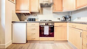 A modern kitchen with wooden cabinets, a Bosch oven, a dishwasher, and a coffee maker.