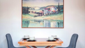 A dining table with four bowls and plates, set against a wall with a landscape painting.