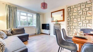 A modern living room with a sofa, dining table, chairs, a TV, and a fireplace.