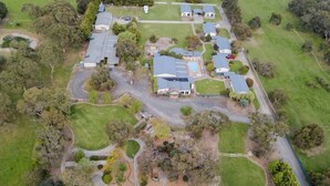 An aerial view of a residential area with multiple houses, a swimming pool, and surrounding greenery.